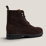 A dark brown suede lace-up boot with a black lug sole, shown from a side profile against a light beige background.