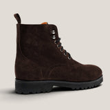 A dark brown suede lace-up boot with a black lug sole, shown from a side profile against a light beige background.