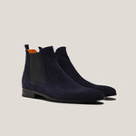 Pair of navy blue suede Chelsea boots on a light beige background