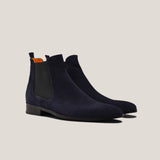 Pair of navy blue suede Chelsea boots on a light beige background