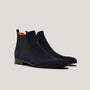 Pair of navy blue suede Chelsea boots on a light beige background