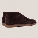 A pair of dark brown suede chukka boots with a brown rubber sole, shown from a side profile view against a light beige background.