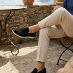 Person sitting outdoors wearing black loafers with a scenic background