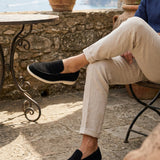 Person sitting outdoors wearing black loafers with a scenic background