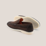 Brown loafers with white soles on a light beige background