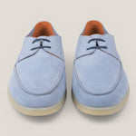 Pair of light blue suede shoes on a beige background