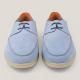 Pair of light blue suede shoes on a beige background