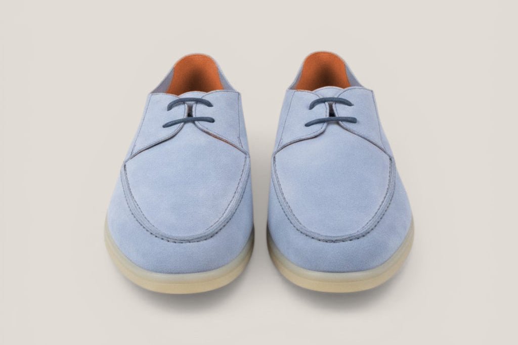 Pair of light blue suede shoes on a beige background