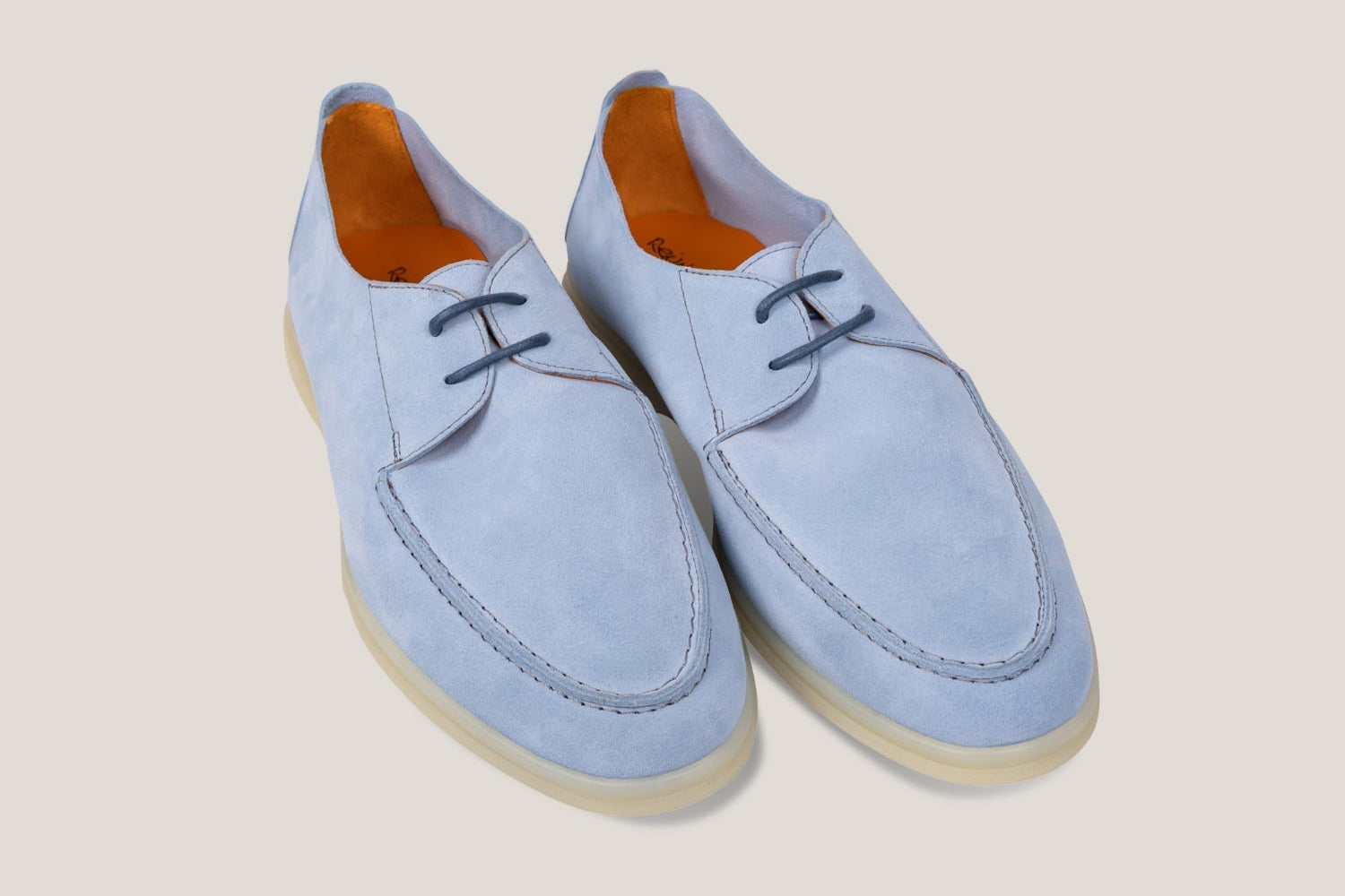 Pair of light blue suede shoes on a beige background