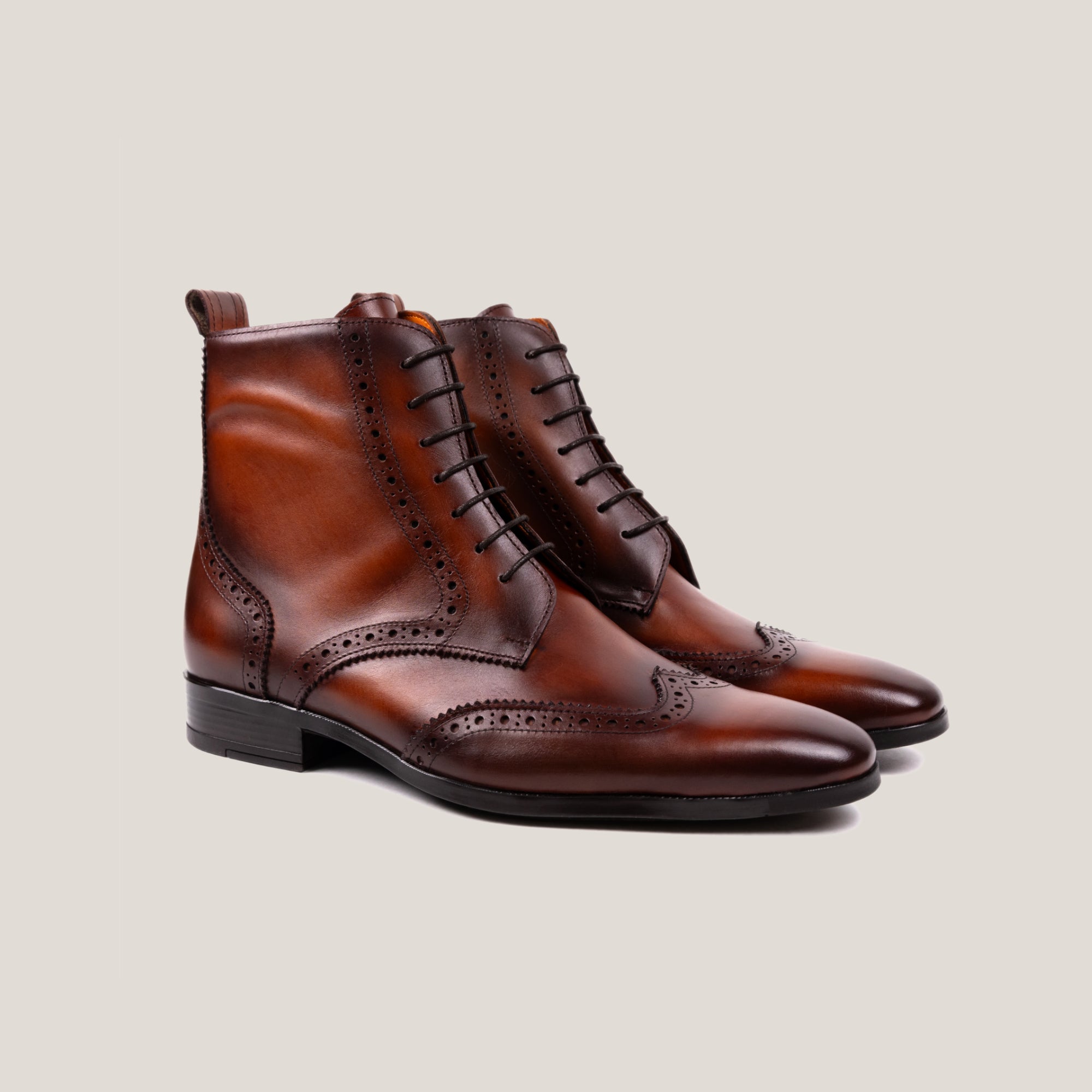 A pair of cognac brown leather full-brogue balmoral boots with lace-up closure and brogue detailing.