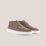Pair of brown suede shoes with white soles on a beige background