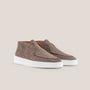 Pair of brown suede shoes with white soles on a beige background