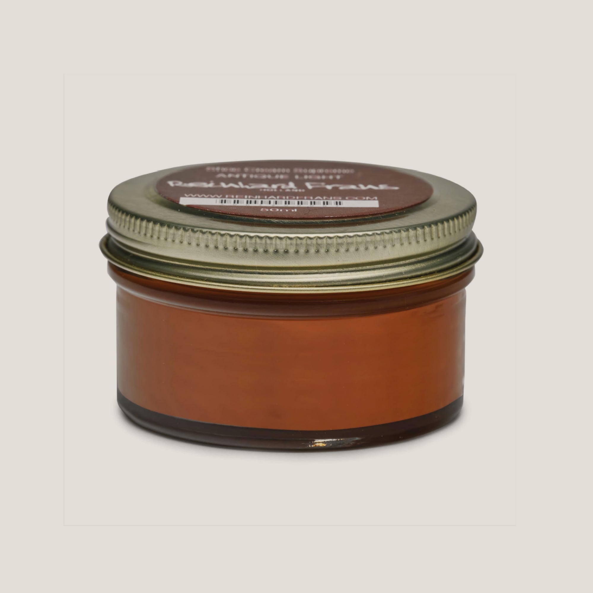 A jar of shoe cream with a label on the lid, the main color of the cream appears to be brown.